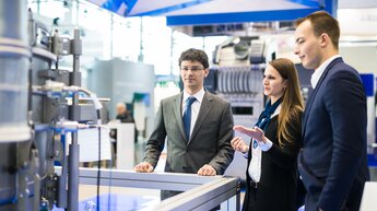 employee and prospective customer at a machine at the trade fair stand | © Allgaier Process Technology 2022