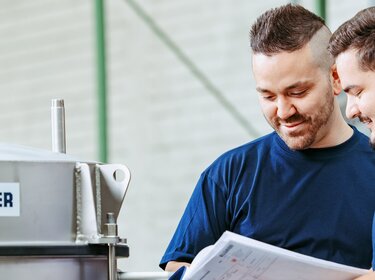 empleados de allgaier trabajando en una máquina de cribado en una sala de producción | © Allgaier Process Technology 2022